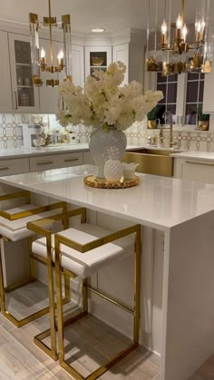 a large white kitchen with gold accents and marble counter tops is pictured in this image