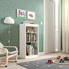 a child's room with green wallpaper and toys on the floor in front of it