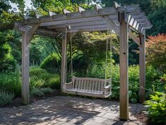 a wooden bench sitting under a pergoline covered arbor in a lush green park