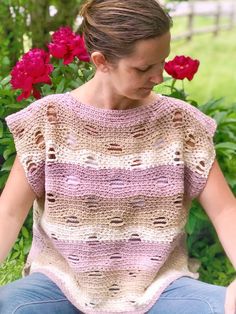 a woman sitting in front of flowers wearing a crocheted sweater with ruffles