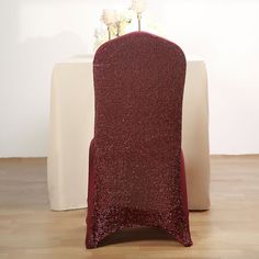 a red chair sitting in front of a white table with flowers on top of it