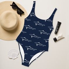 a bathing suit, hat, sunglasses and sunscreen on a white table with shells