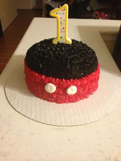 a red and black cake with a one candle on top