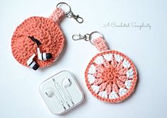 two crocheted keychains with ear buds attached to them, one is pink and the other is white