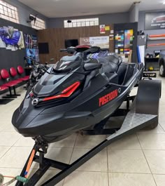 a black and red jet ski on display in a showroom with other snowmobiles