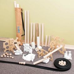 an assortment of wooden toys sitting on the floor next to a bag and some sticks