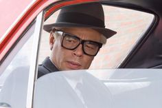 a man wearing glasses and a hat sitting in a car