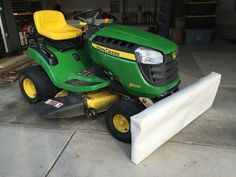 a green lawn mower parked in a garage