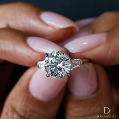 a woman holding a diamond ring in her hands with the center stone on it's side