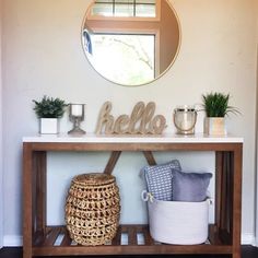 a wooden table topped with a mirror next to a basket and potted plant on top of it