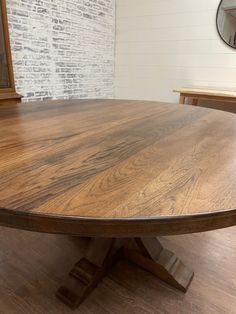 a round wooden table sitting on top of a hard wood floor next to a mirror