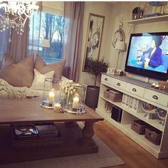 a living room filled with furniture and a flat screen tv sitting on top of a wooden table