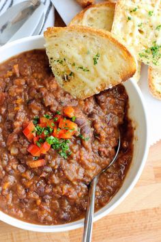 a bowl filled with beans and bread on top of a wooden table