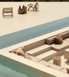 an empty pool with lounge chairs next to it and a bench on the side by the water