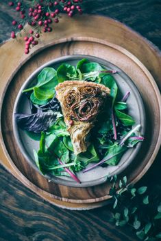 a white plate topped with a slice of pizza on top of green leafy greens