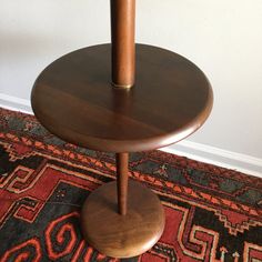 a wooden table sitting on top of a rug next to a white wall and floor