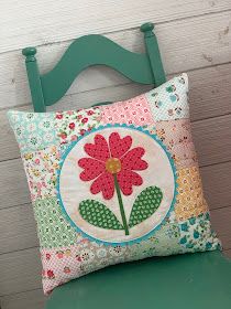 a green chair with a pillow on it and a flower in the center that has been sewn