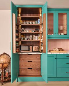 an open cabinet in the middle of a kitchen filled with lots of cupboards and drawers