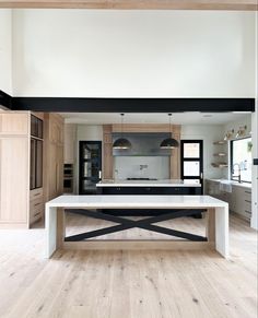 an open kitchen and dining room with wood flooring, white counter tops and black accents