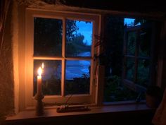 a lit candle sitting on top of a window sill