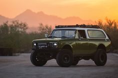 an off - road vehicle is parked in the middle of a parking lot at sunset