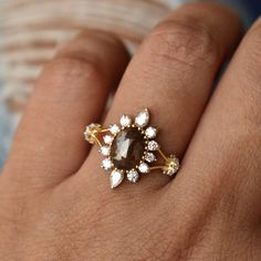 a woman's hand with a ring on it that has a brown and white stone in the middle