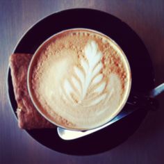 a cappuccino on a black plate with a spoon