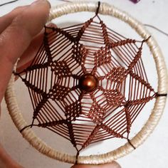 a person holding a small piece of wire with a spider web design on the side