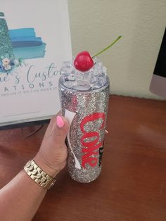 a woman holding up a cup with a cherry on it and a sign in the background