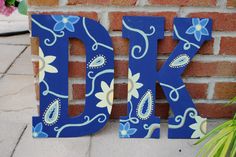 the letter dk is painted blue and yellow with flowers on it's side