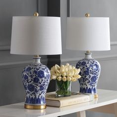 two blue and white vases sitting on top of a table next to a lamp