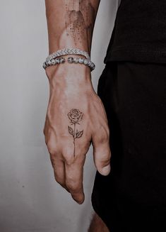 a person's hand with a rose tattoo on it and a chain around the wrist