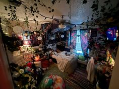 a messy bedroom with lots of clutter on the floor and decorations hanging from the ceiling