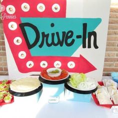 a drive - in sign sitting on top of a table filled with food