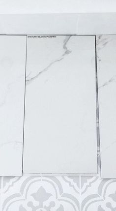 three square white tiles sitting next to each other on top of a wall with grey and white designs