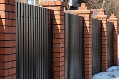 a fence made of red bricks with snow on the ground