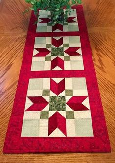 a table runner with red and green stars on it, next to a potted plant