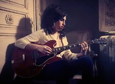 a woman sitting in a chair playing an electric guitar