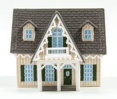 a crocheted doll house with blue windows and green shutters on the front