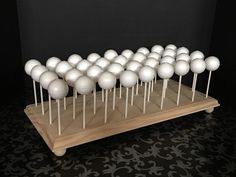 a bunch of white balls are on top of some wooden sticks in front of a black wall