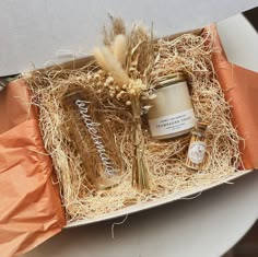 an open gift box with candles and some dried plants in it on top of a table