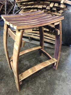 a wooden stool sitting on top of a floor next to a pile of wood planks