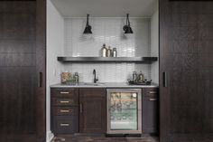 a kitchen with dark wood cabinets and white tile backsplashing on the wall