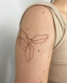 a woman with a tattoo on her arm that has two leaves drawn on it's shoulder