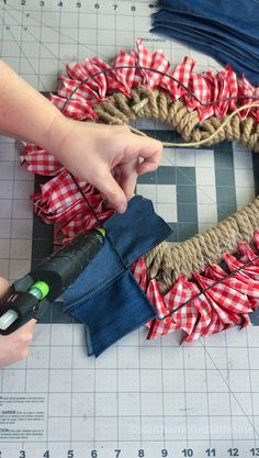 someone is making a wreath out of old jeans and burlocks with a pair of scissors