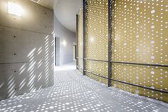 an empty hallway with yellow walls and white dots on the wall is lit by a spot light