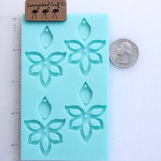 a penny sitting next to a cookie sheet with flowers on it and leaves cut out