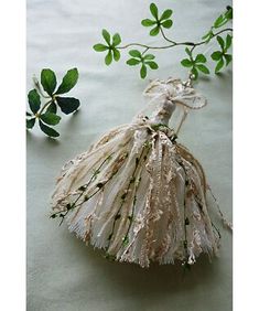 an ornament is hanging from a branch with green leaves on the table next to it