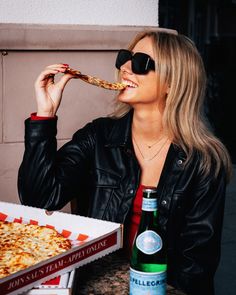 a woman is eating pizza and drinking beer