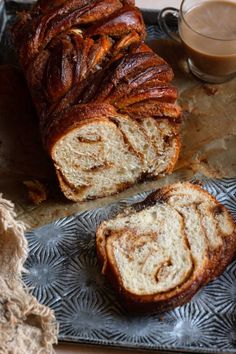 a loaf of cinnamon swirl bread sitting on top of a metal tray next to a cup of coffee